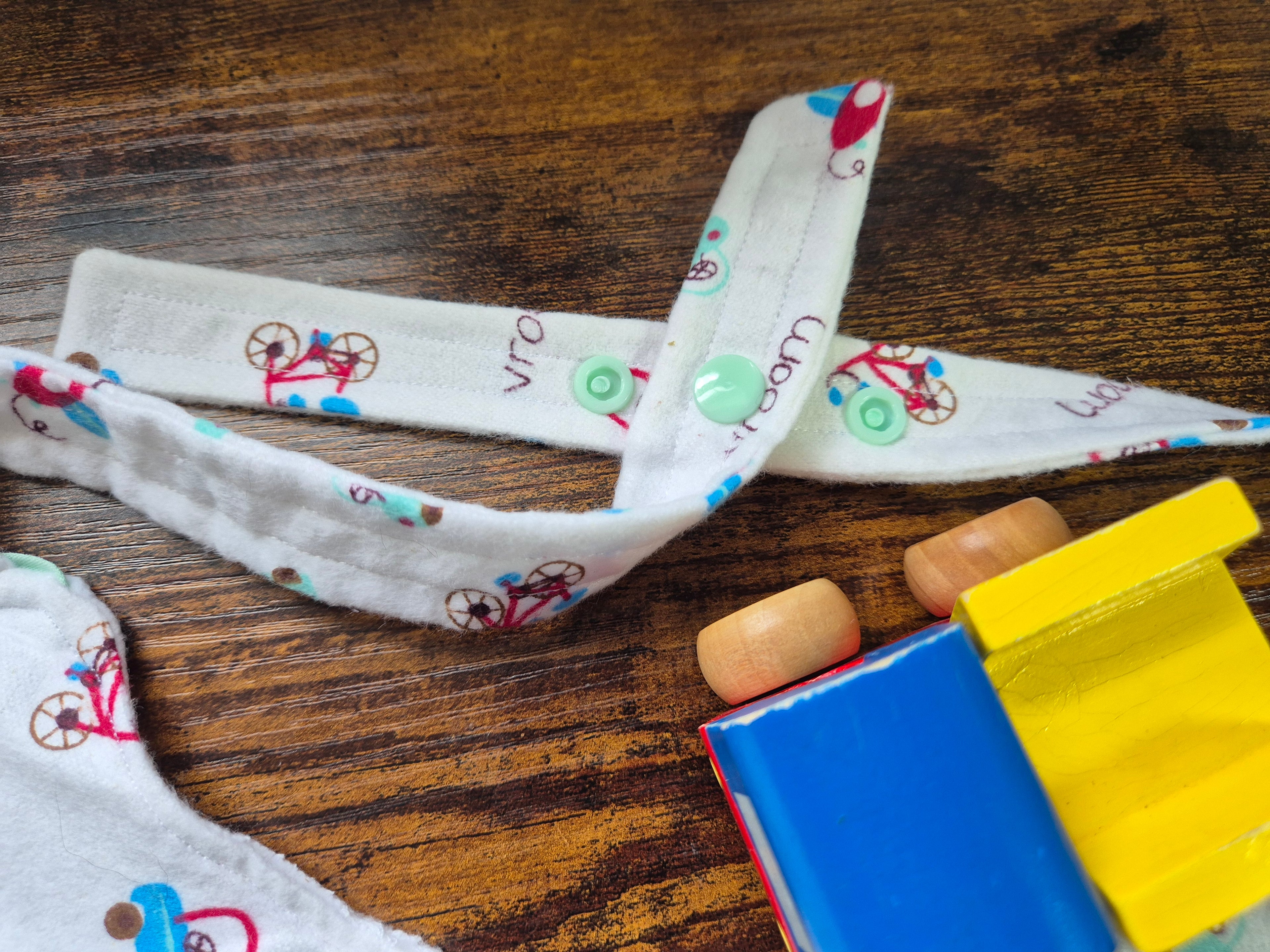 Fabric straps with cartoon designs on a wooden surface with colorful snap fasteners