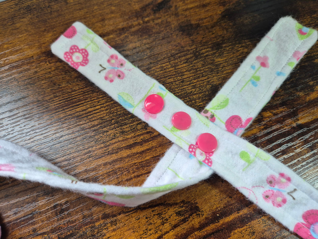 Fabric strap with floral pattern showing coloured snap fasteners on a wooden surface