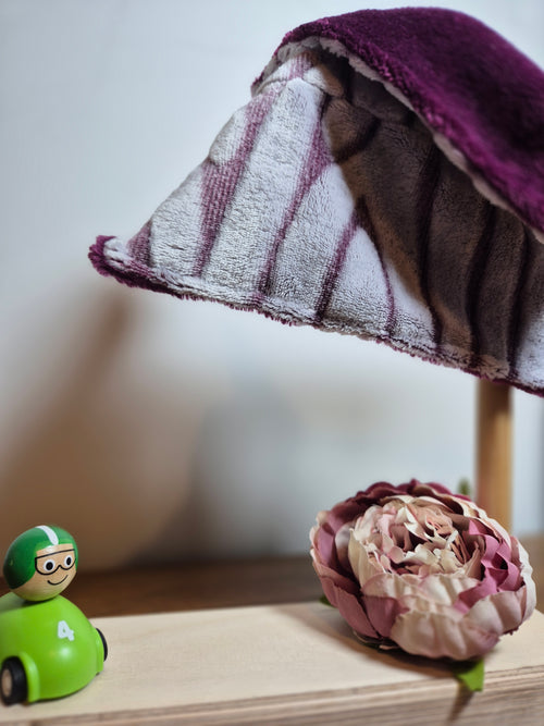 Close up of purple and gray animal striped fleece comforter on stand with flower and toy