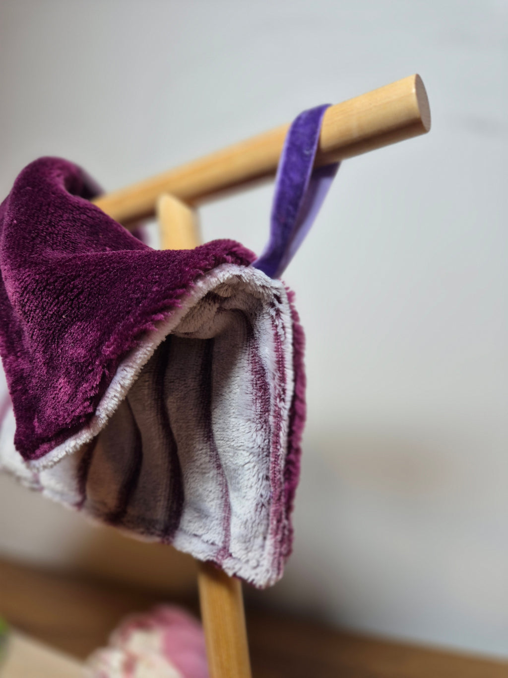 Close up of ribbon loop attached to comforter displayed on wooden stand. 