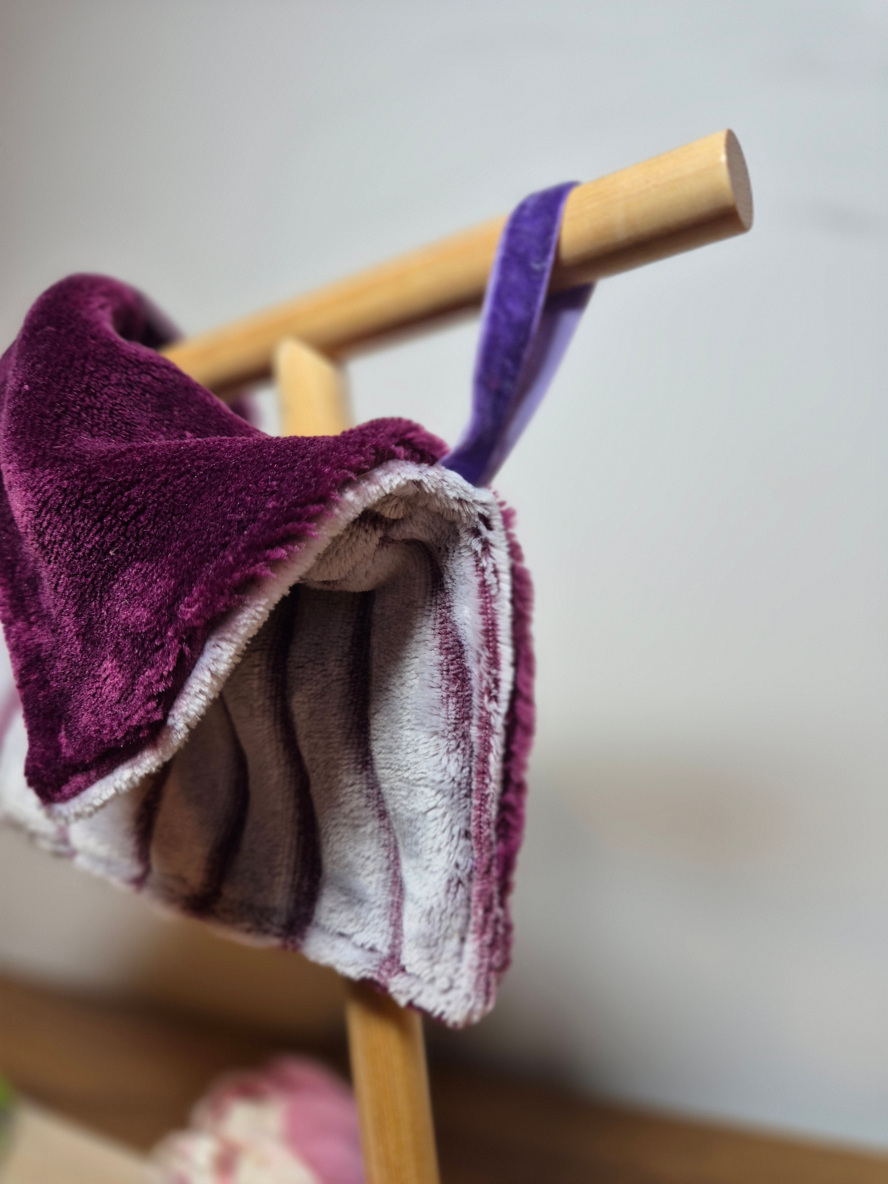 Close up of ribbon loop attached to comforter displayed on wooden stand. 