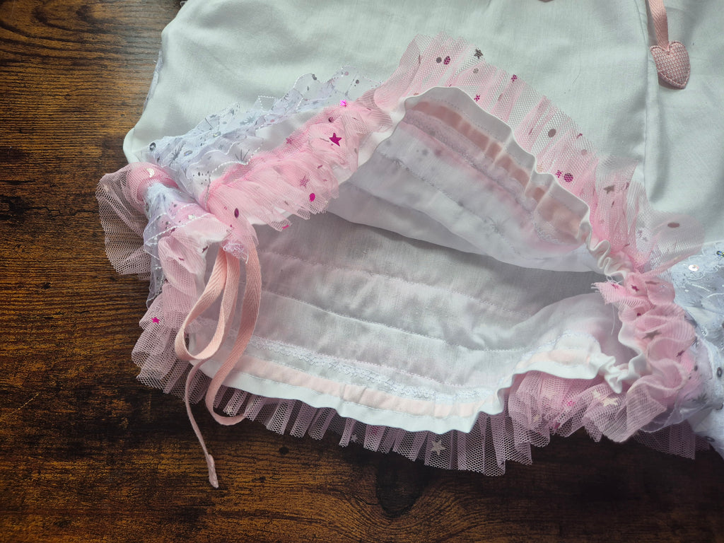Apeture of leg opening of white drawers with pink ruffles, showing drawstring cord -  on a wooden 
surface.sissy knickers, adult baby nappy cover, victorian style drawers, unisex