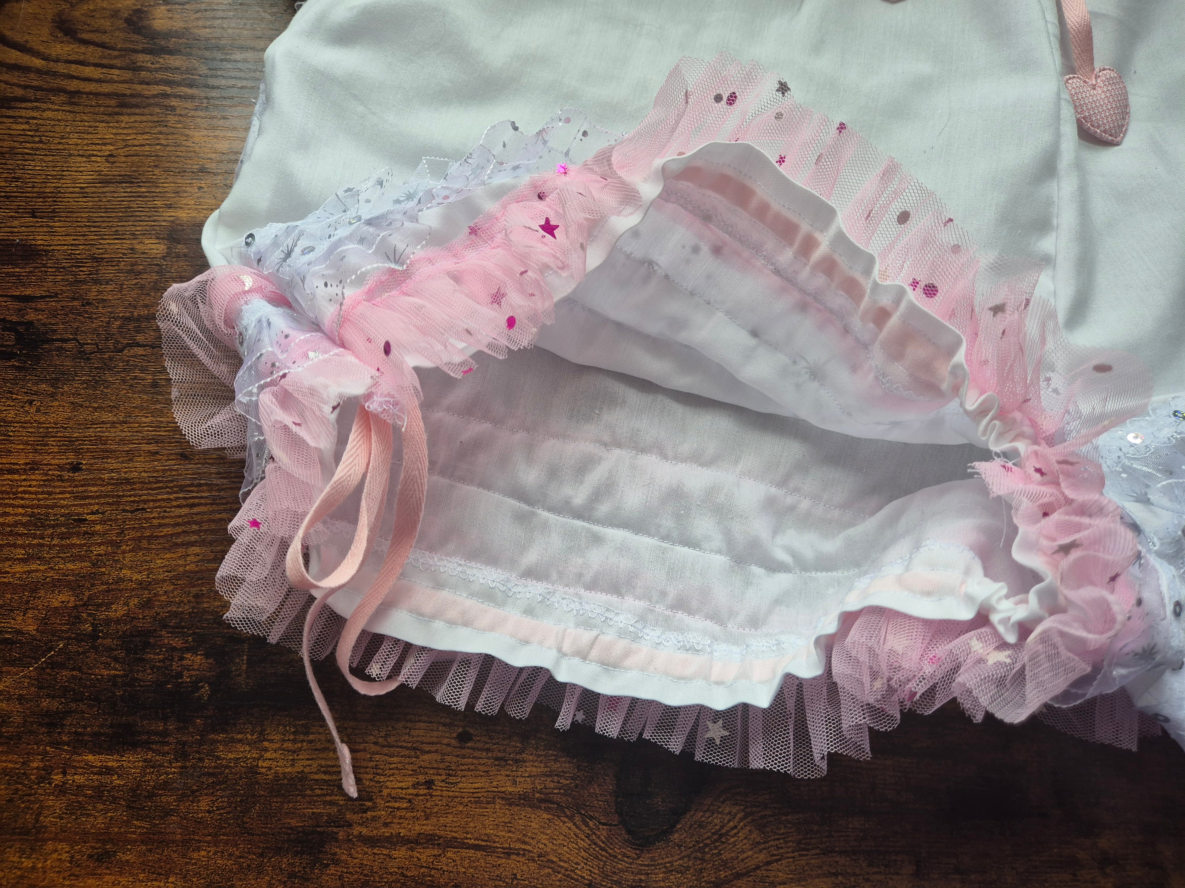 Apeture of leg opening of white drawers with pink ruffles, showing drawstring cord -  on a wooden 
surface.sissy knickers, adult baby nappy cover, victorian style drawers, unisex