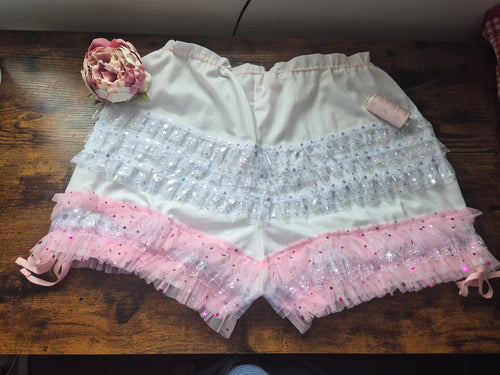 White shorts with pink trim on a wooden surface. sissy knickers, adult baby nappy cover, victorian style drawers, unisex