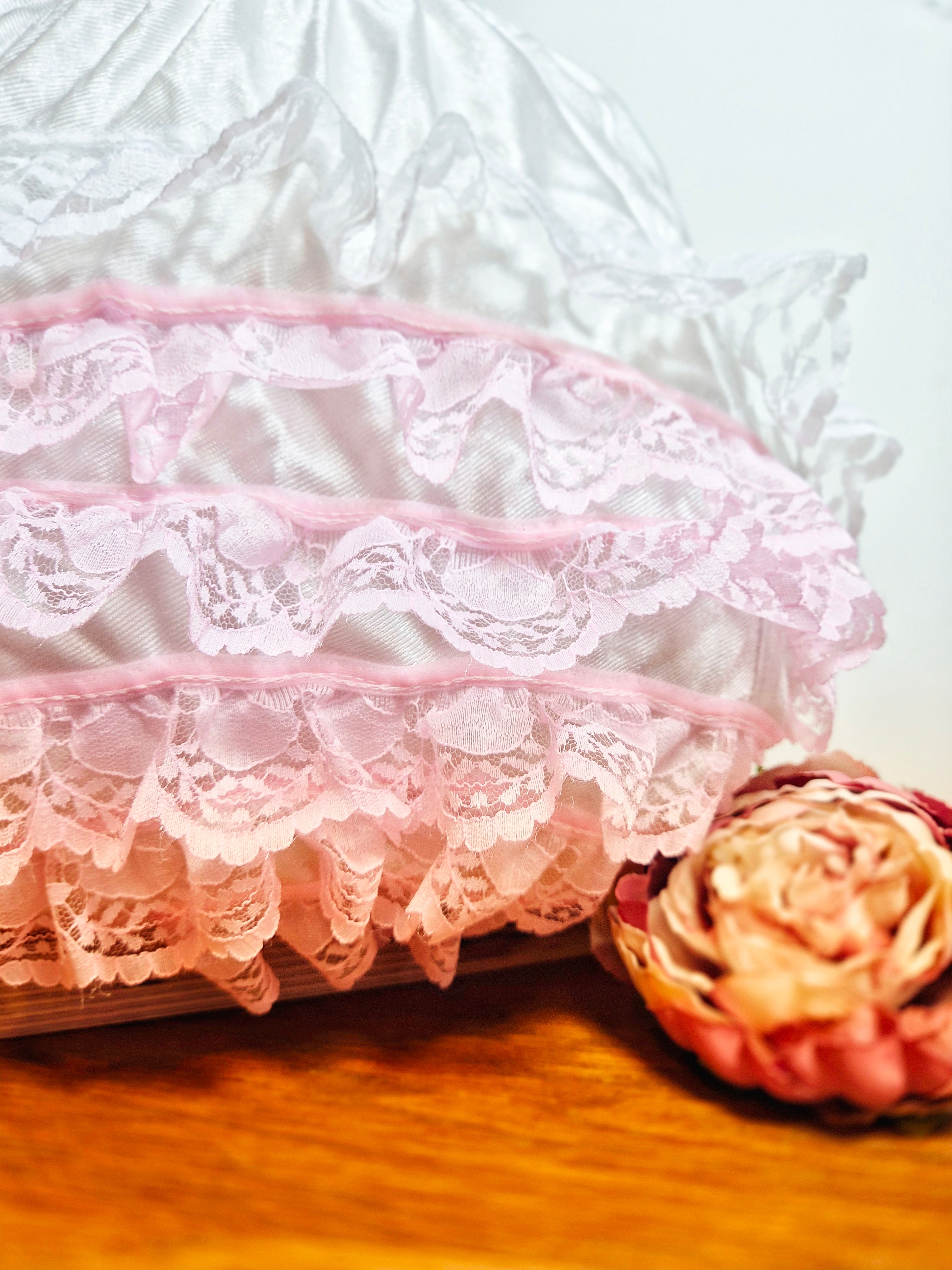 Close-up of Kitty Nylon Knickers showing layered white and pink lace ruffle trim  detail and fabric rose