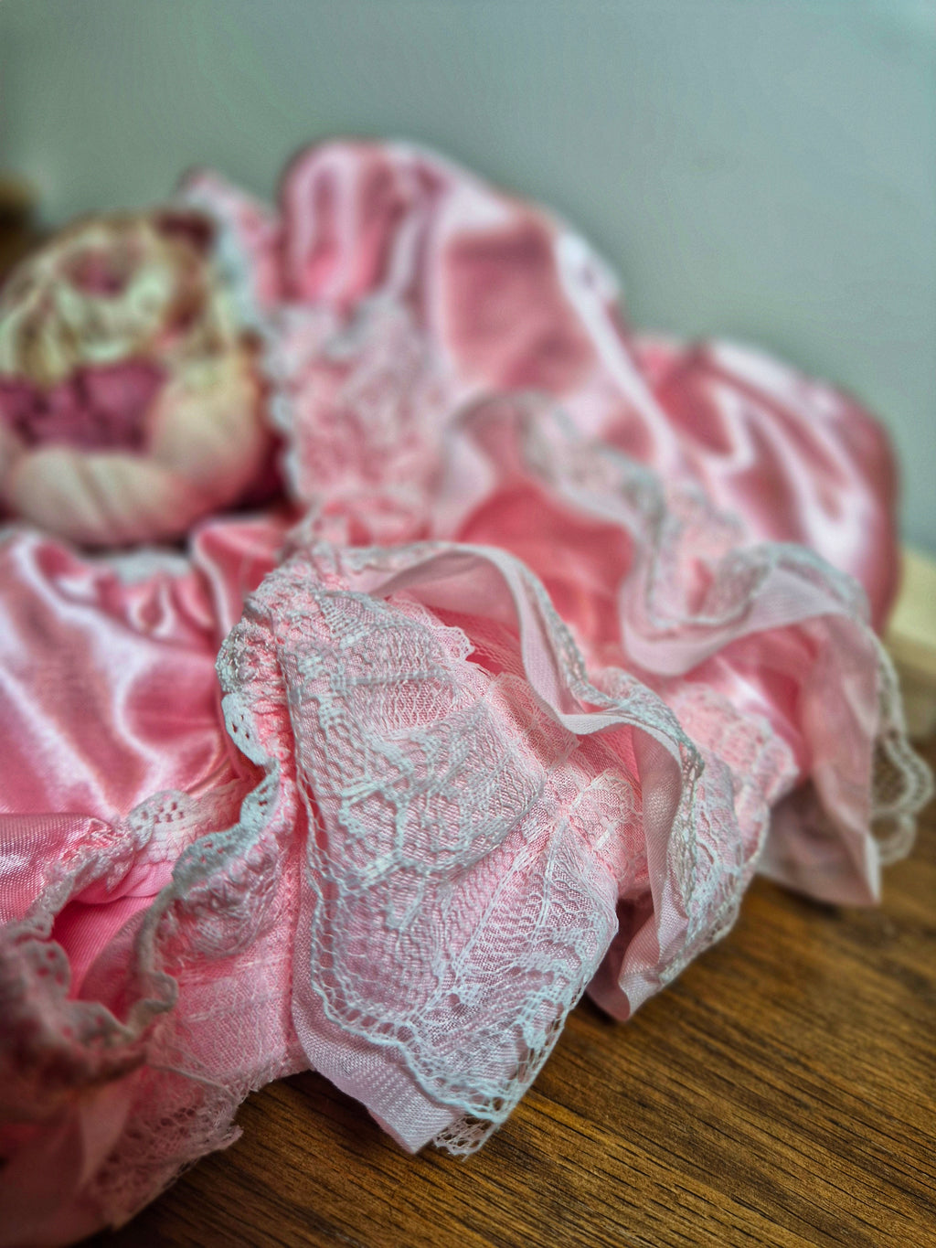 Satin and Lace ruffled panties lying on a wooden surface with flower detail. 
