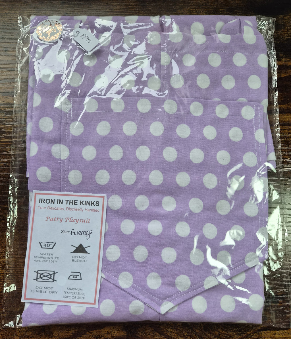 Iron in the Kinks Patty Playsuit in purple and white spot floral print in clear packaging  and care label, size Average — wash at 40°C, do not bleach, do not tumble dry, iron max 150°C