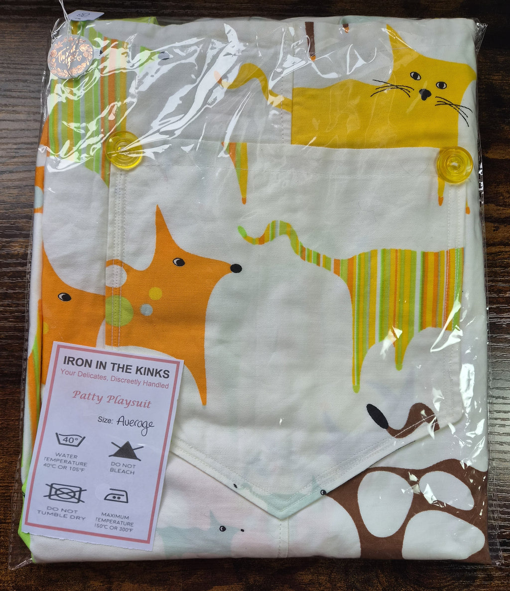 Iron in the Kinks Patty Playsuit, white with abstract animals in clear packaging. care label, size Average — wash at 40°C, do not bleach, do not tumble dry, iron max 150°C