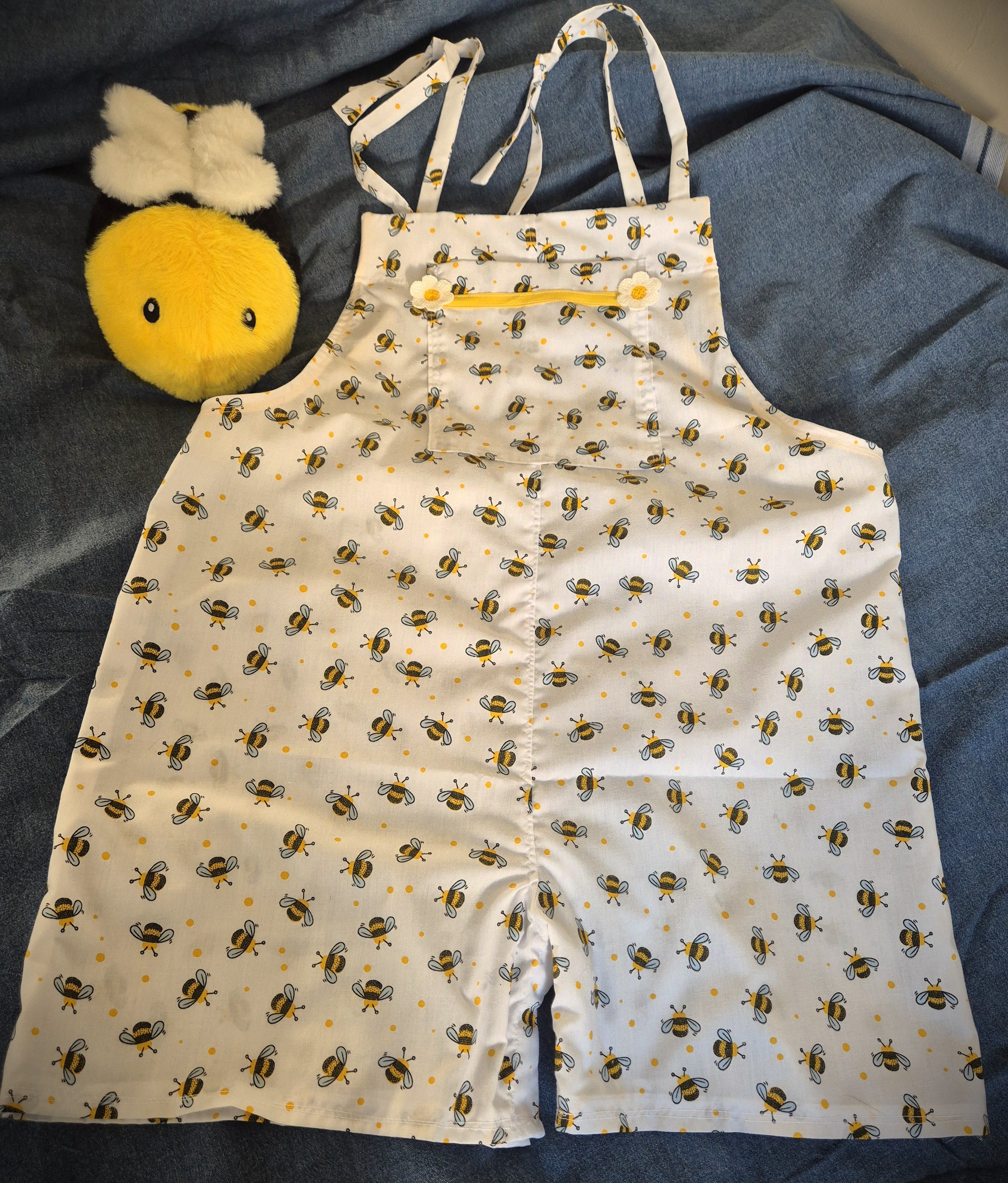 Patty Playsuit in white bumble bee and yellow polka dot print, front view flat with yellow chest pocket trim and crochet daisy detail