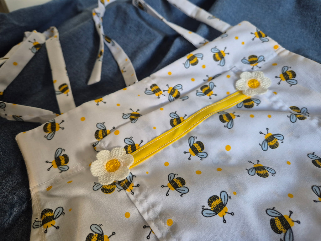 Patty Playsuit in white bumble bee print, three-quarter view on dress form showing tie shoulder straps and chest pocket with yellow binding