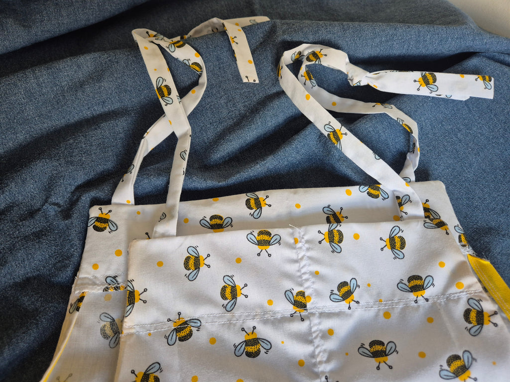 Back view of Patty Playsuit in white bumble bee print laid flat showing tie shoulder straps. Adult baby

