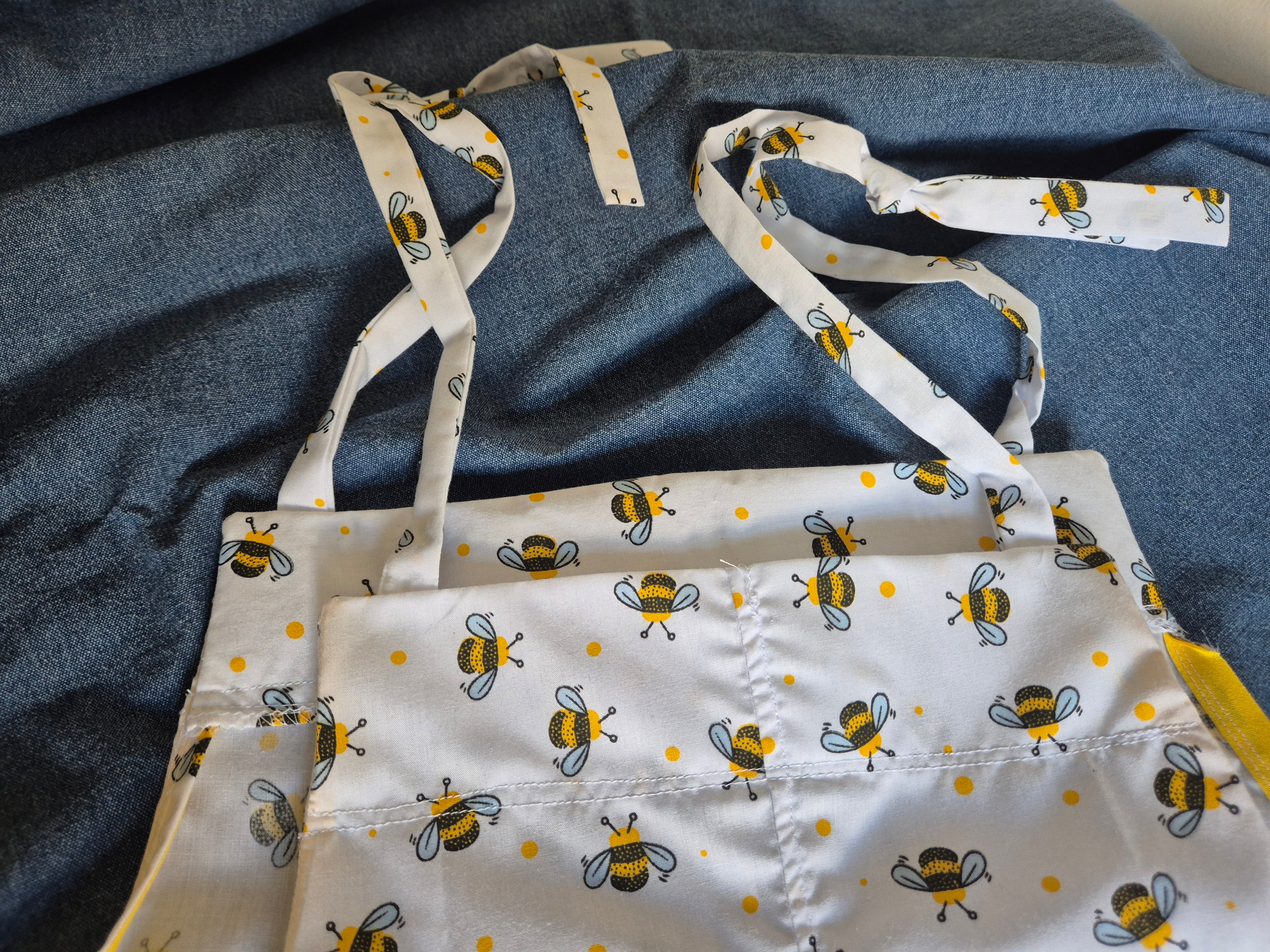 Back view of Patty Playsuit in white bumble bee print laid flat showing tie shoulder straps. Adult baby
