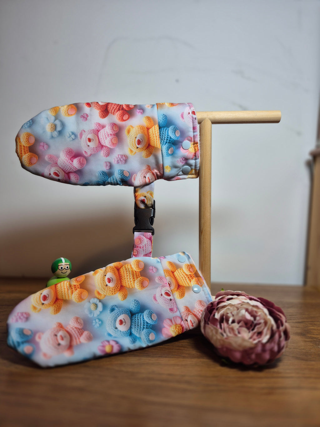 Smitten scratch cuffs with a stand showing safety clip, photographed on a dark wooden surface.