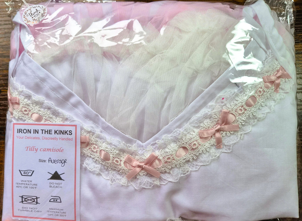 Iron in the Kinks Tilly Camisole in white with broderie anglaise and pink ribbon trim in clear packaging with care label, size Average — wash at 40°C, do not bleach, do not tumble dry, iron at max 150°C
