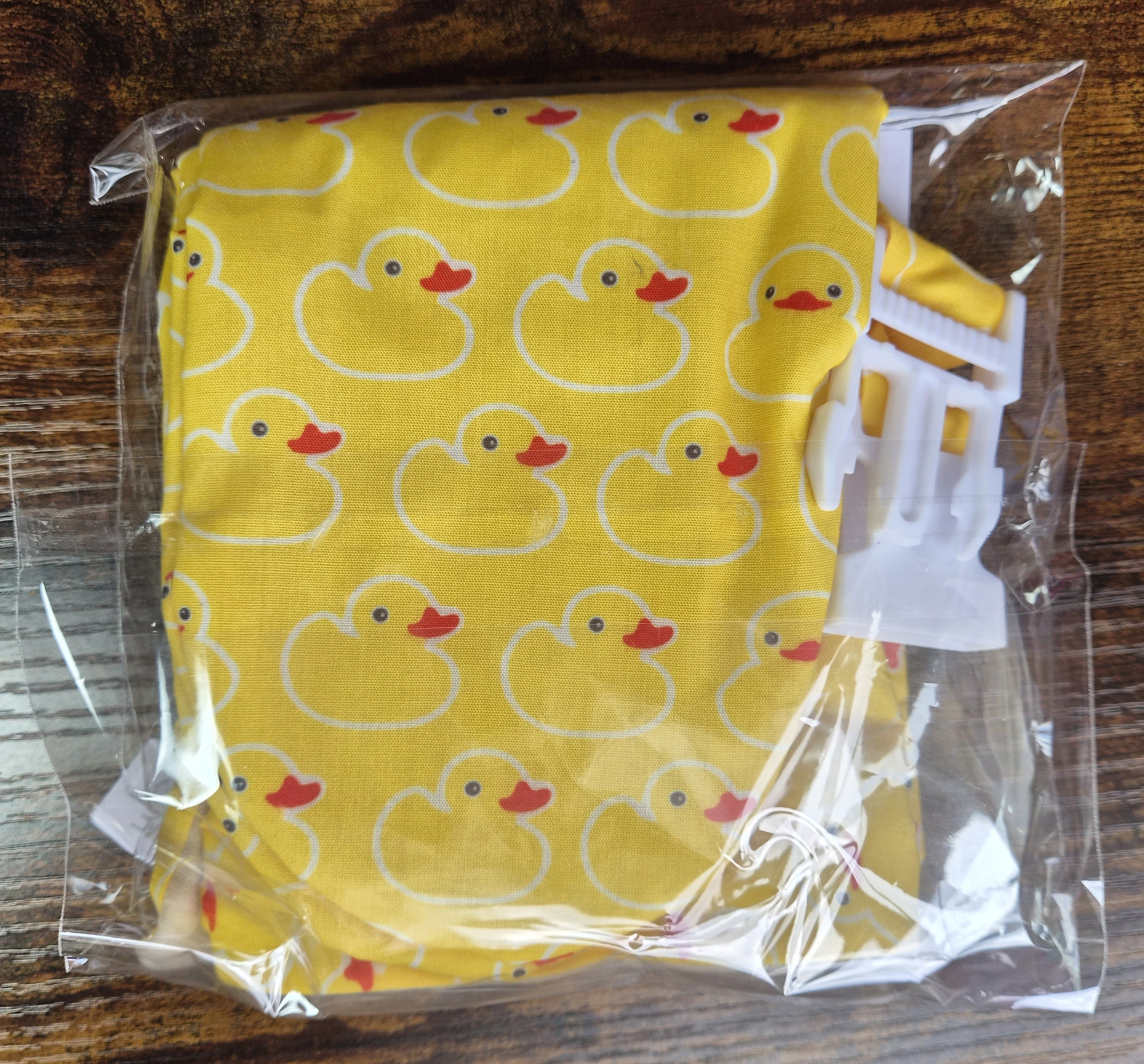 Yellow duck patterned scratch mittens in celophane wrapper with safety clip to secure the pair